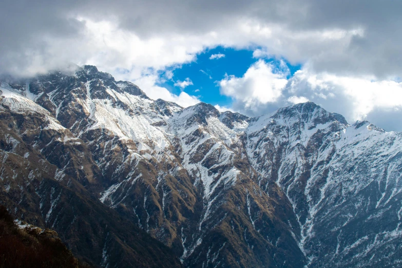 two mountains are shown covered in snow with clouds in the background