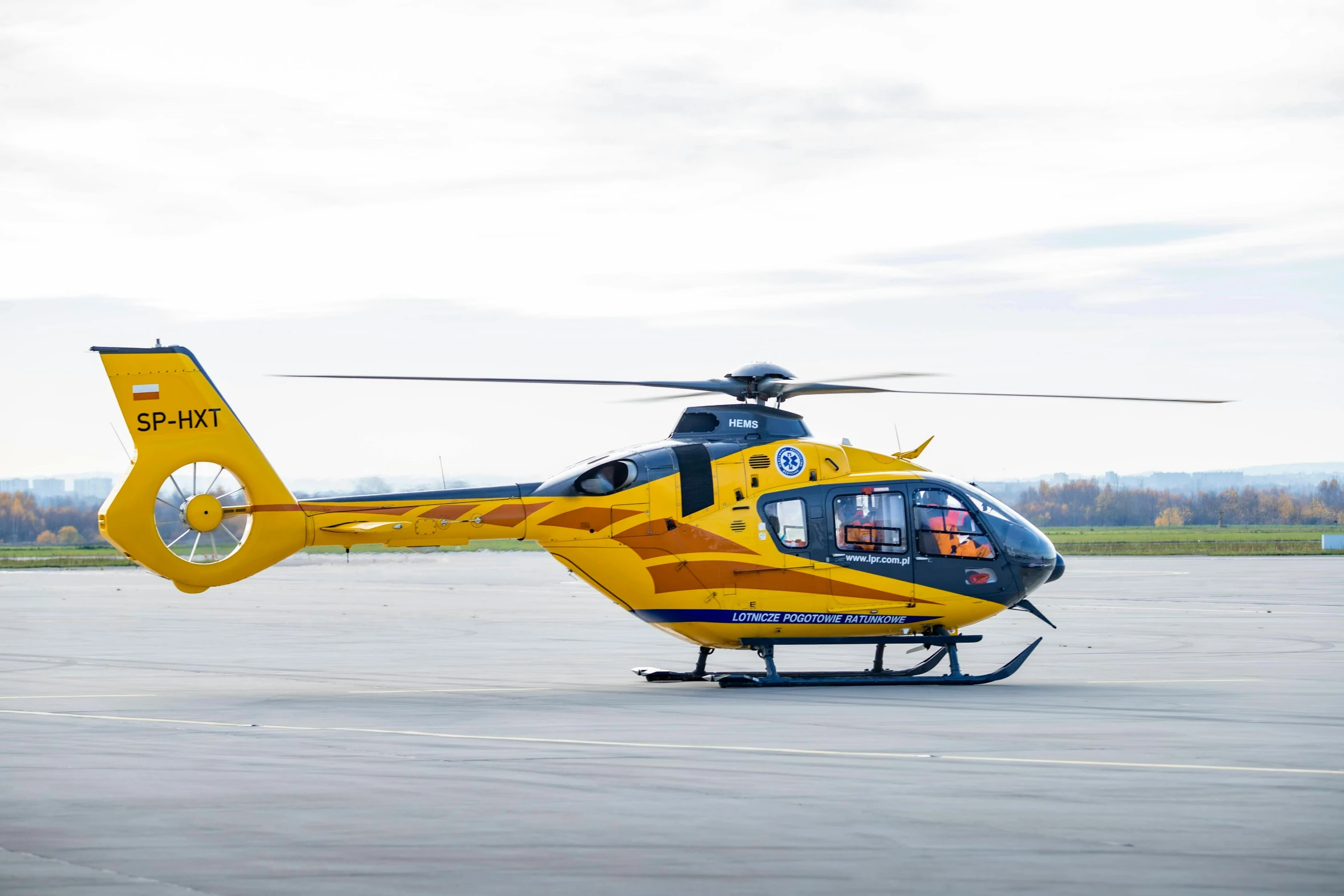 the yellow helicopter is parked on the pavement