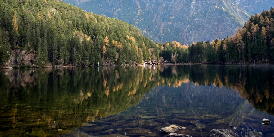 a lake surrounded by trees is shown with mountains in the background