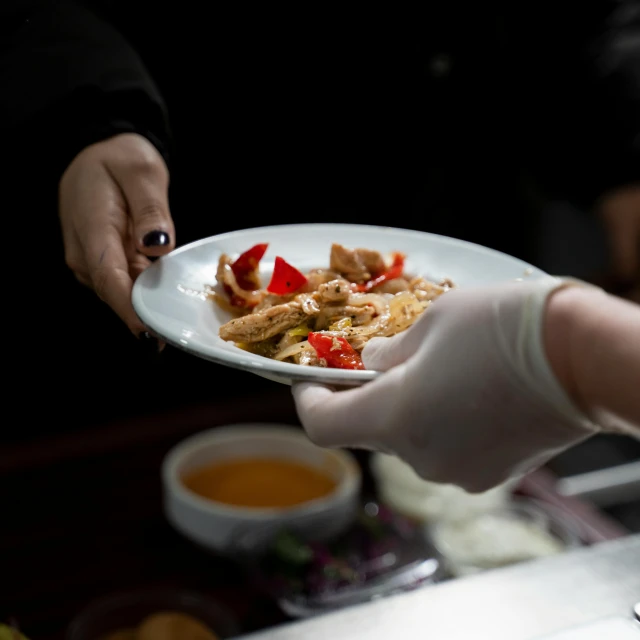 some hands in gloves are serving food to others