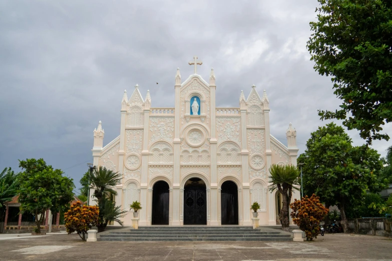 an ornate church is painted white under a cloudy sky