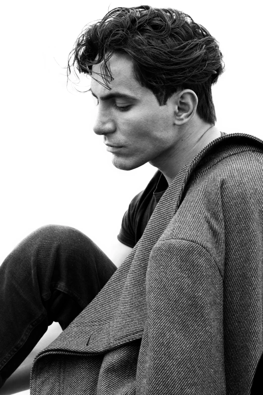 a young man is sitting on the ground and looks down at his phone