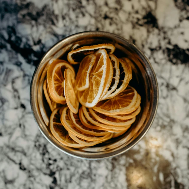 peeled orange peels in a metal bowl on a marble table