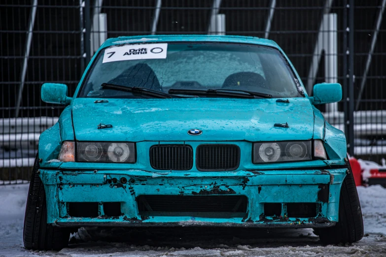 the front end of a teal, blue, vintage bmw, with a sticker stating, ` seven and zero '