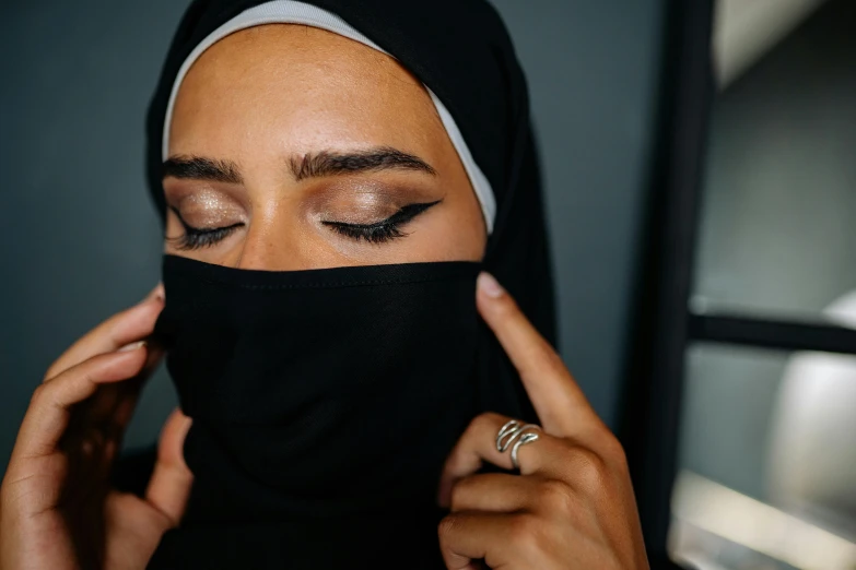 a woman wearing a black veil and ring on her finger