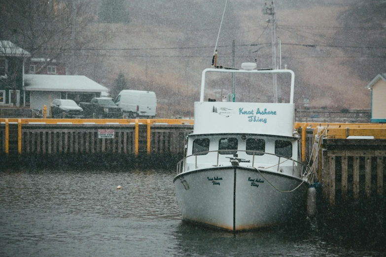 a white boat sits in the water at a dock in the snow