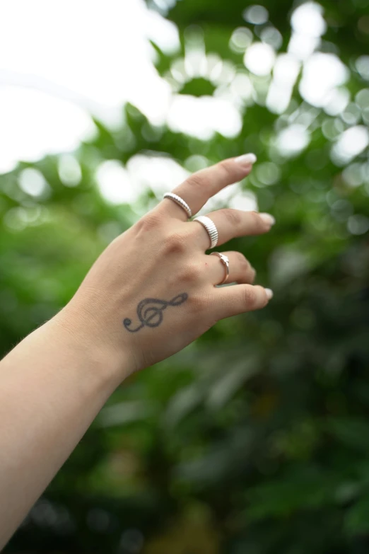 a person wearing a ring and showing their hand with a flower tattooed on it