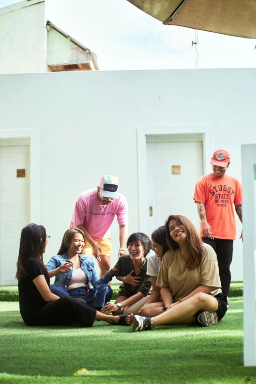 a group of people are sitting on grass next to some doors