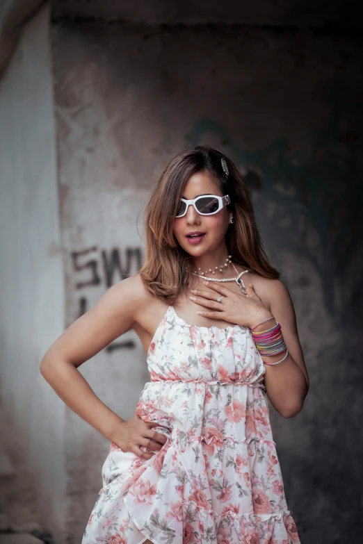 a woman wearing white sunglasses standing with her hands on her hip