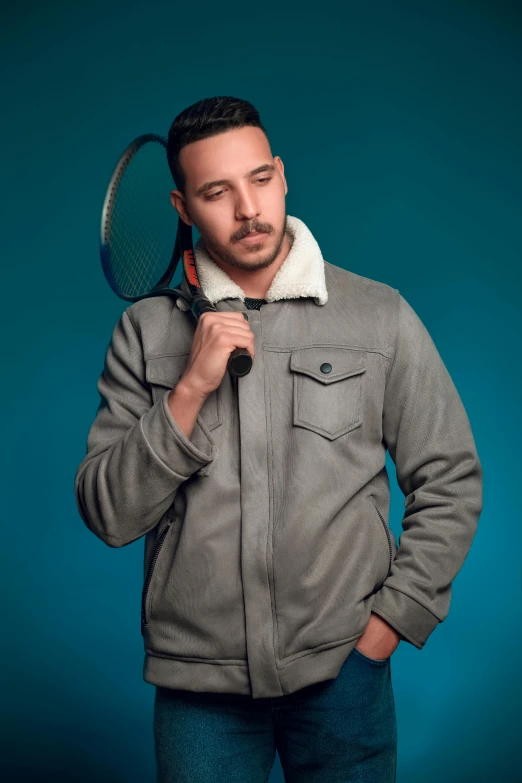 a man holding a tennis racket and wearing a jacket