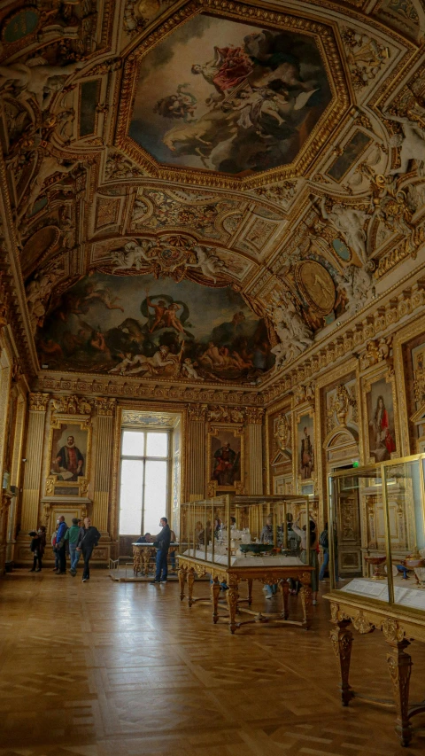 an elaborate room has painted ceilings, a gold chandelier, and paintings