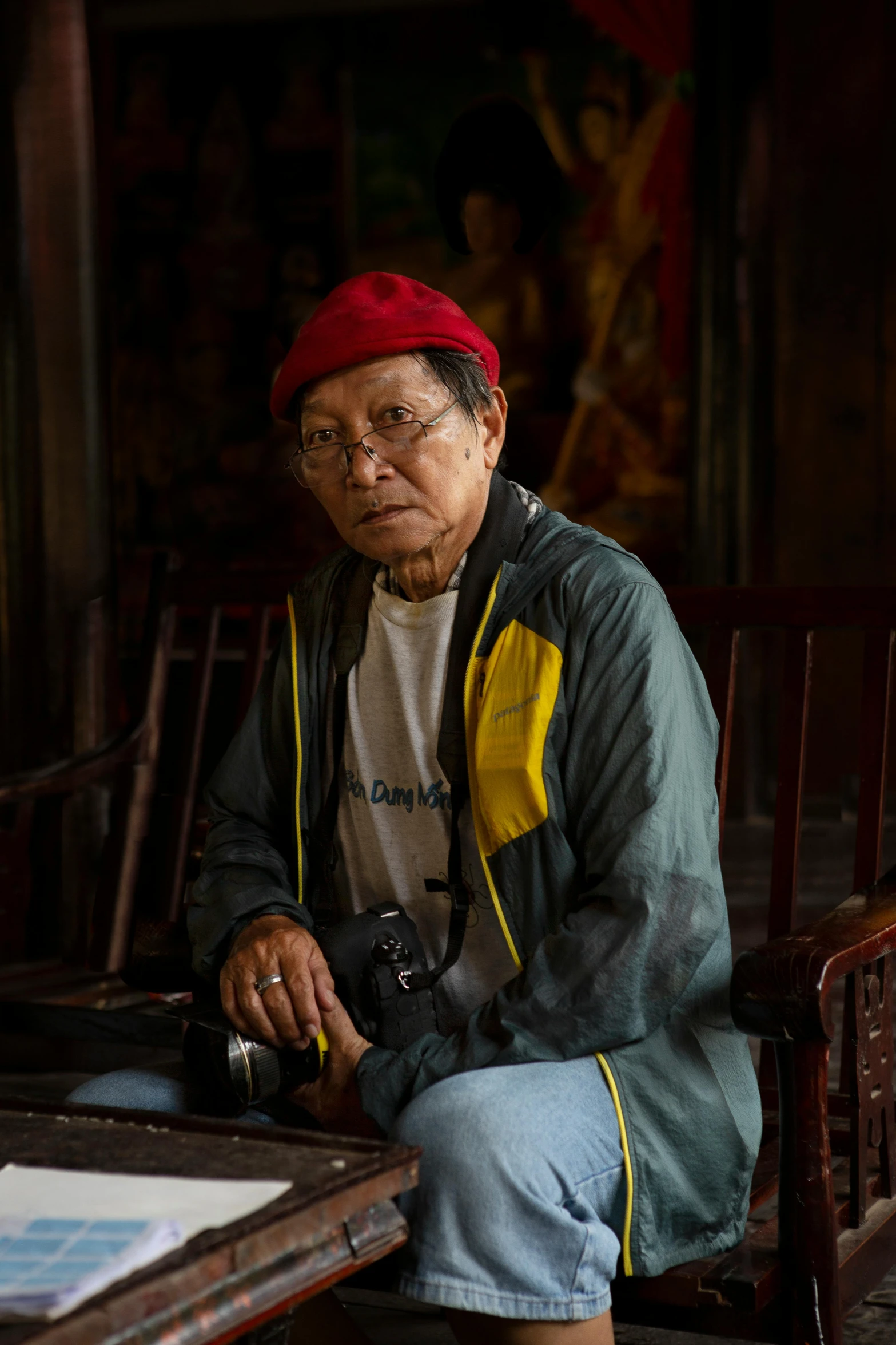 an elderly woman sits at a desk with her camera in hand