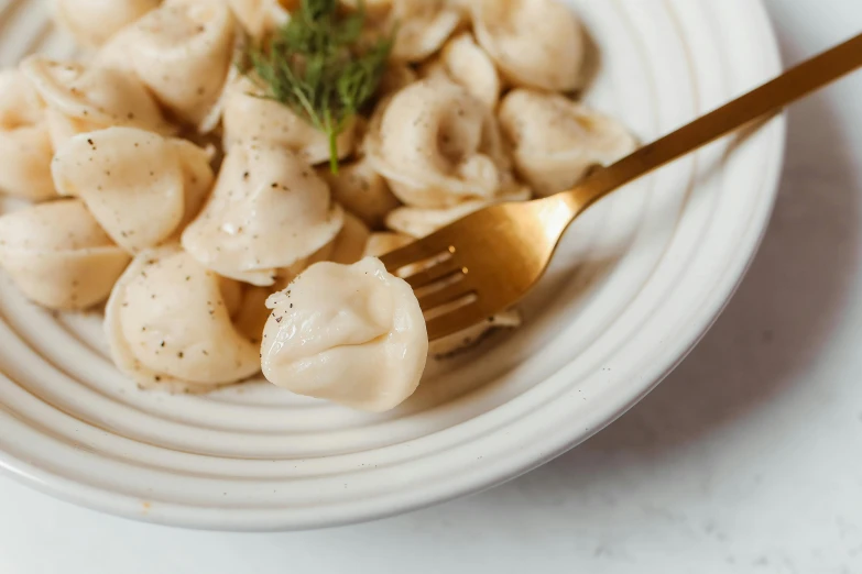 a white plate holding dumplings with a gold fork