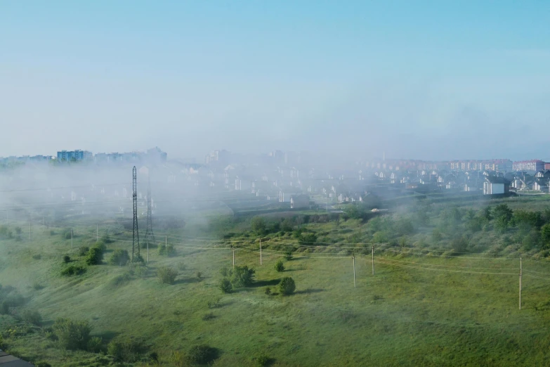 fog moving through a landscape with trees and buildings