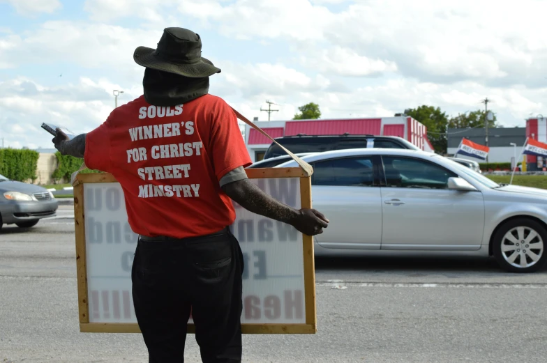 a black guy standing on the side of the street with a sign in his hand