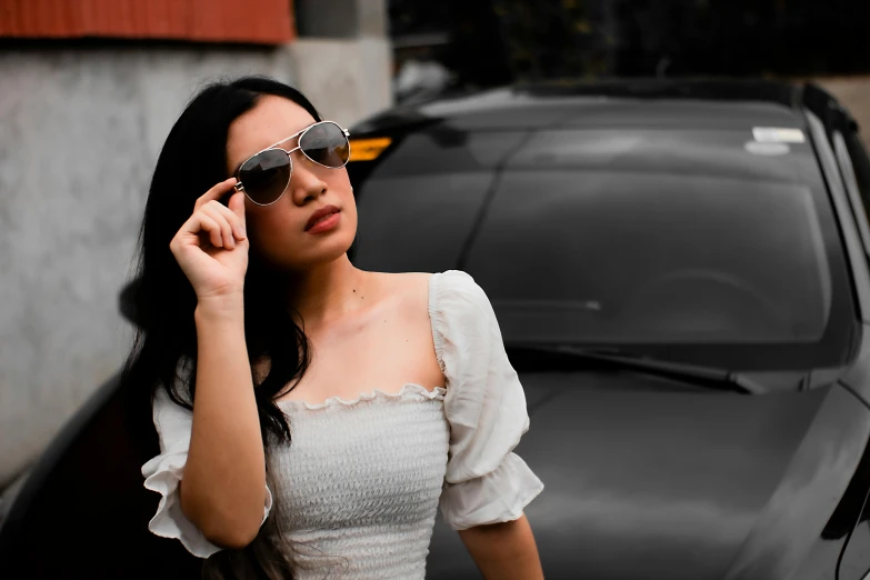 a woman in a dress wearing sunglasses next to a car