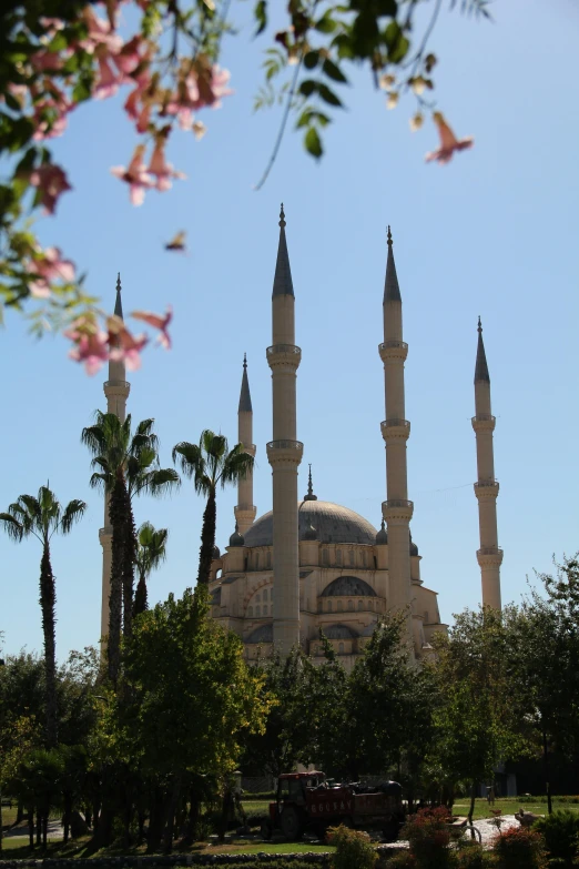 a white mosque sitting in front of a flowery tree