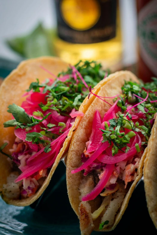 two tacos sitting on a plate next to a beer bottle