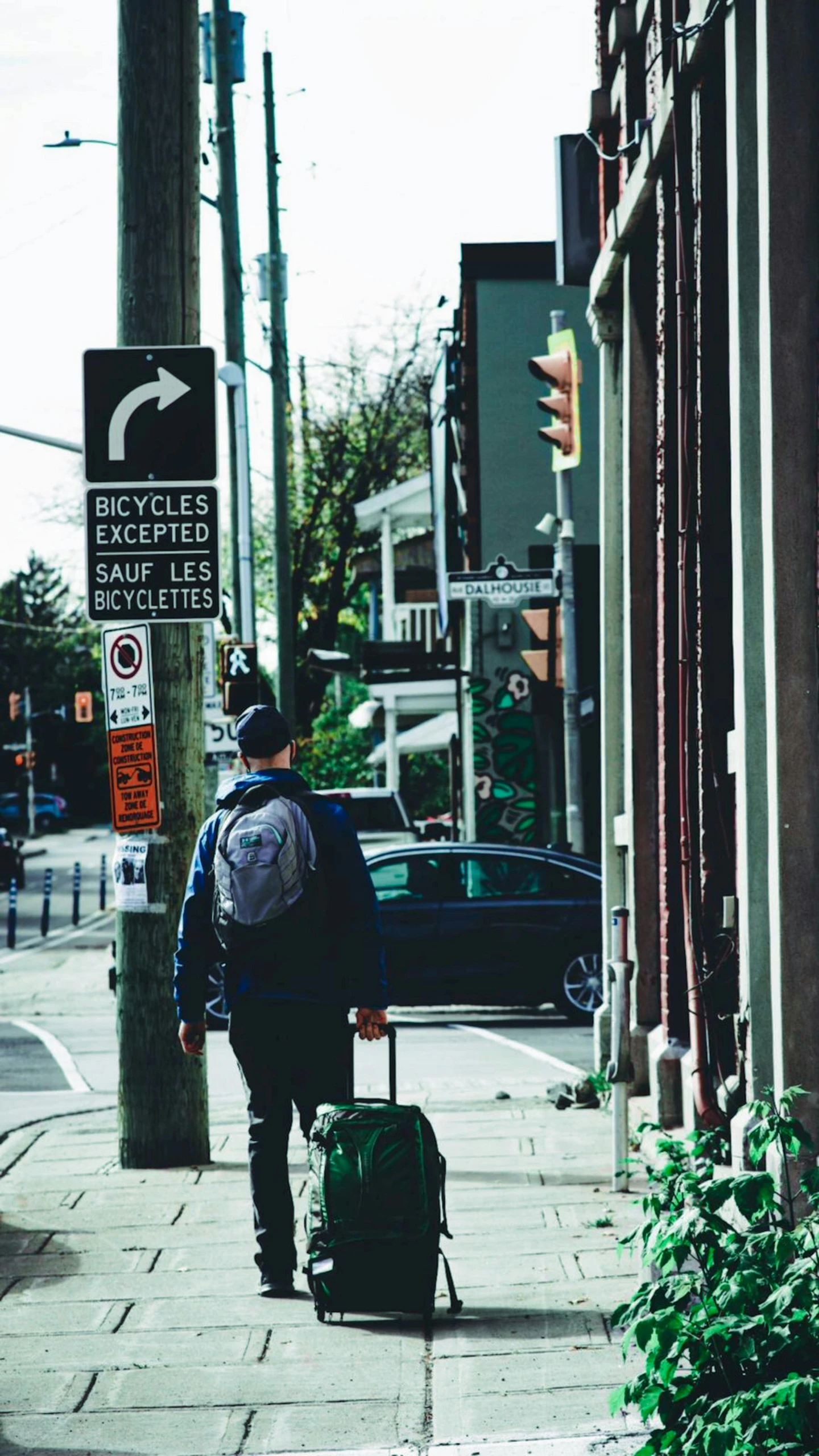 a man carrying luggage on the sidewalk near the street