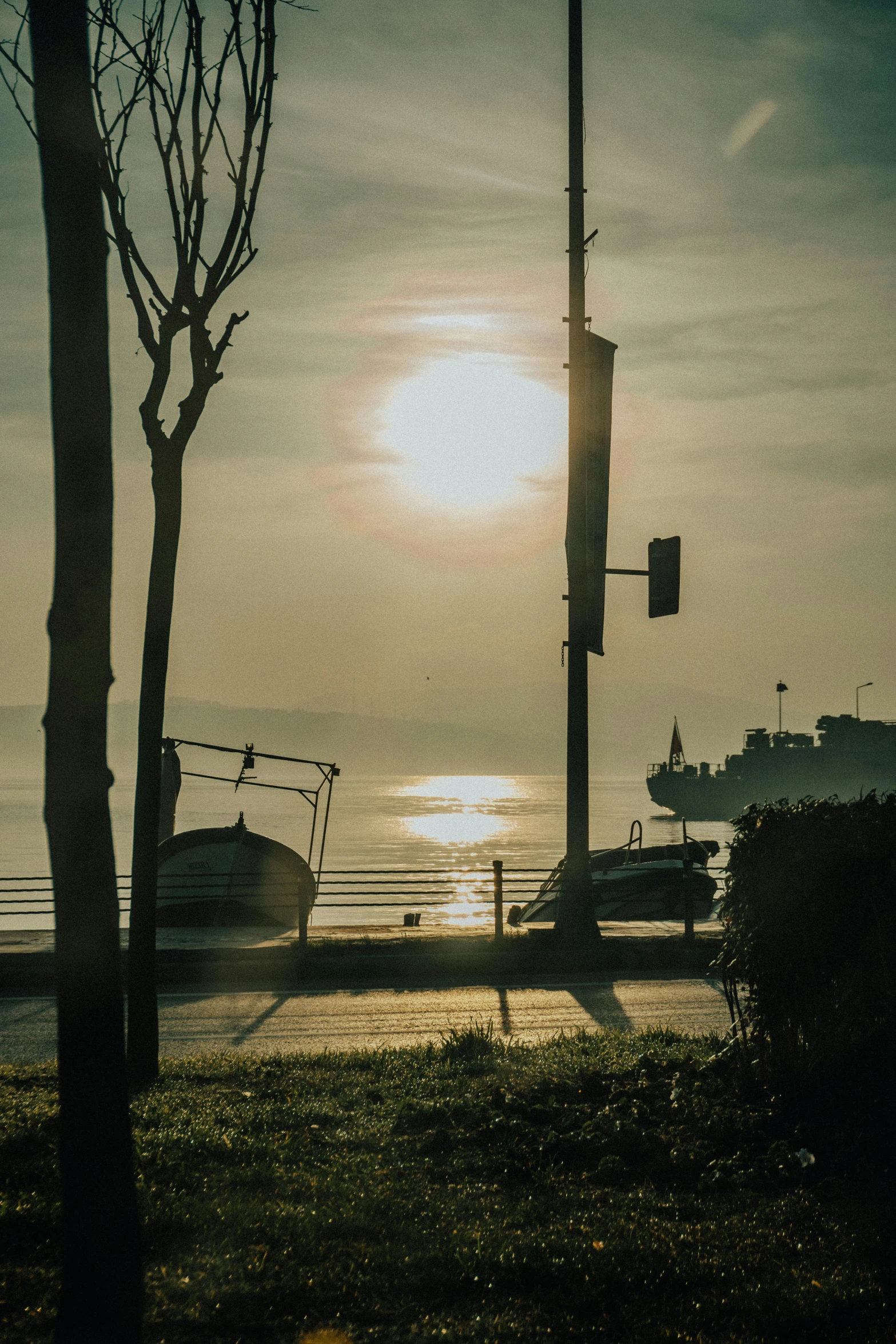 the sun is setting over a harbor with large boats on it