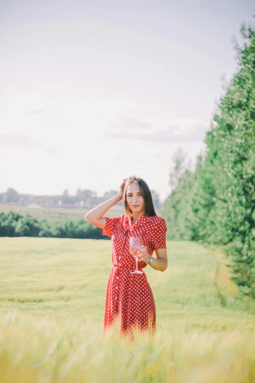 a woman in a red and white dress stands in an open field