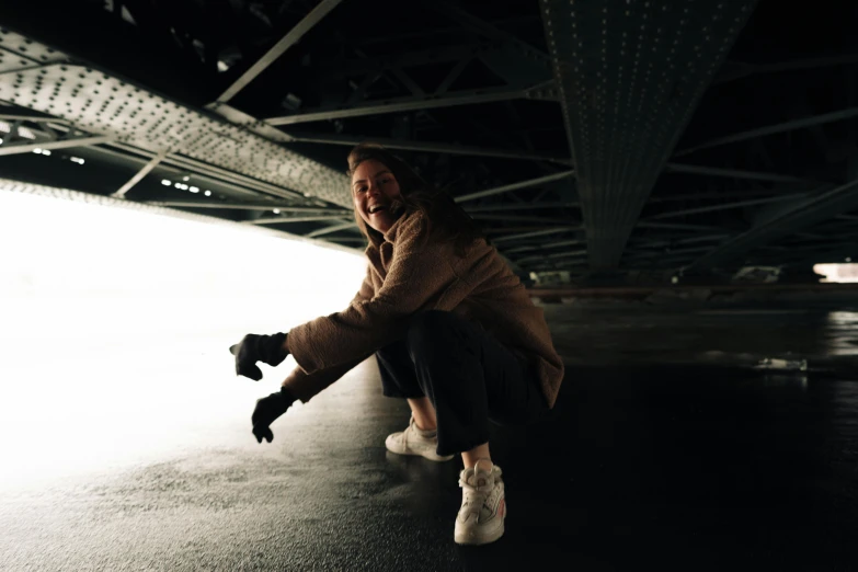 a woman in winter clothes skateboards on a dark pavement