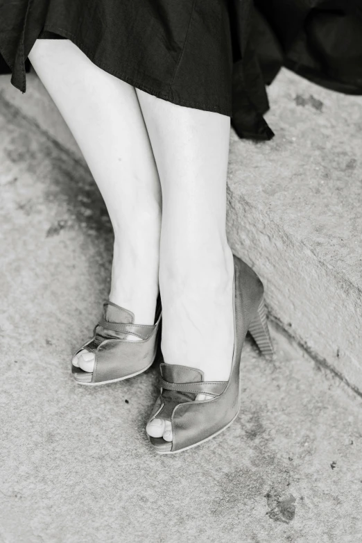 woman's feet and legs in shoes while sitting on ledge