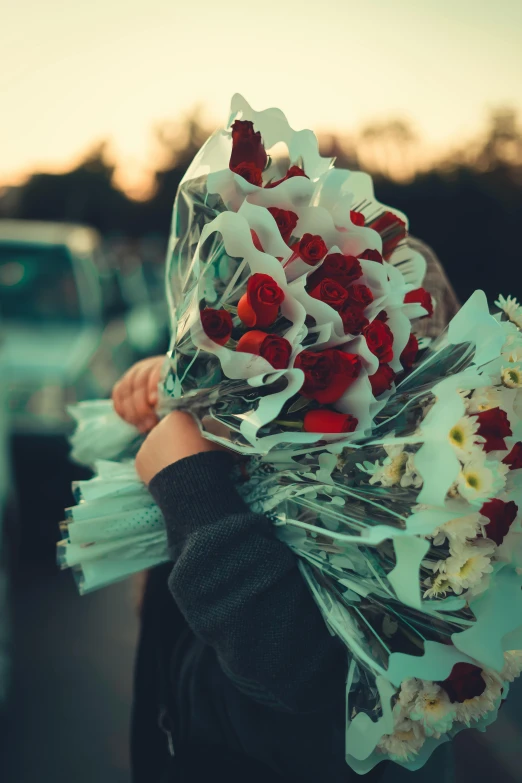 someone is holding up flowers outside