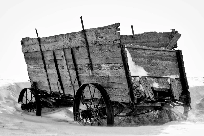 an old wooden wagon with wheels is traveling through snow