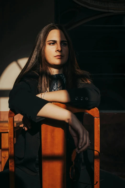 a woman in a black shirt sitting in a chair with her arms folded