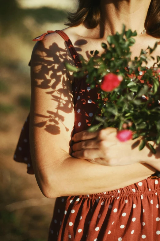 a woman holds a small bush of red flowers