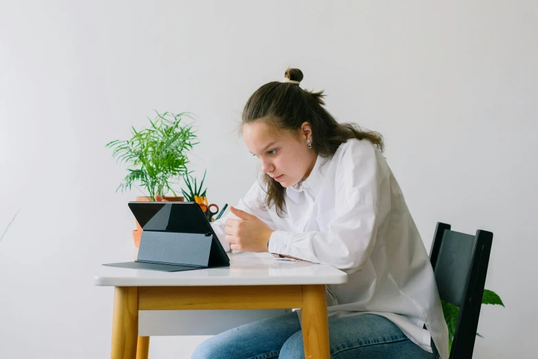 a woman sitting at a table with an apple laptop