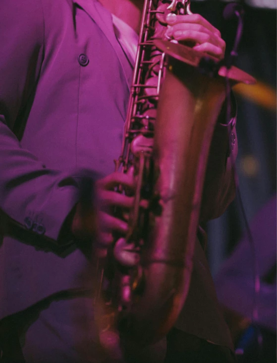 the person wearing a black suit is playing the saxophone