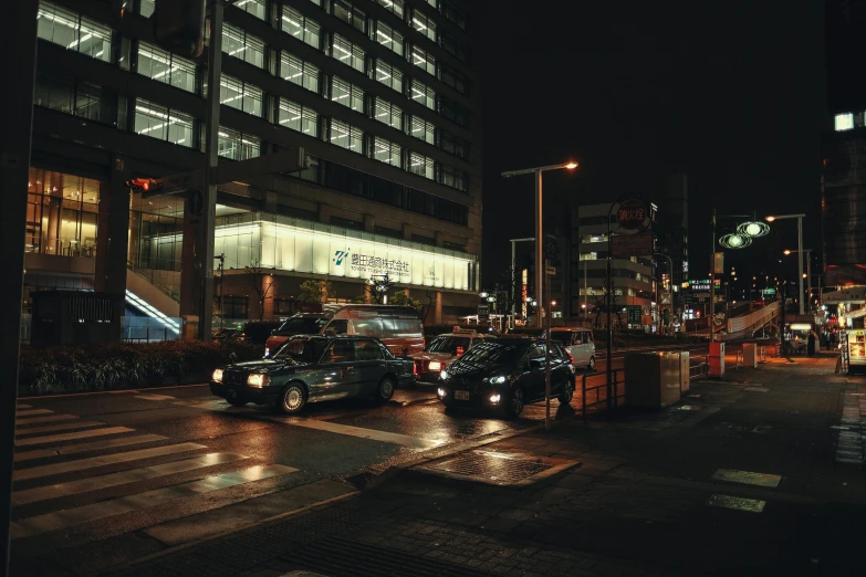 two taxi cabs are parked near a busy intersection at night