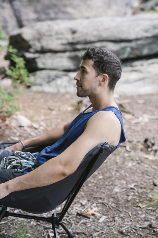 man sitting outside in chair looking towards the water