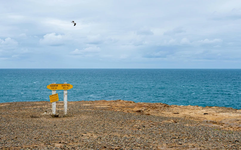 a sign that is on top of a hill by the ocean