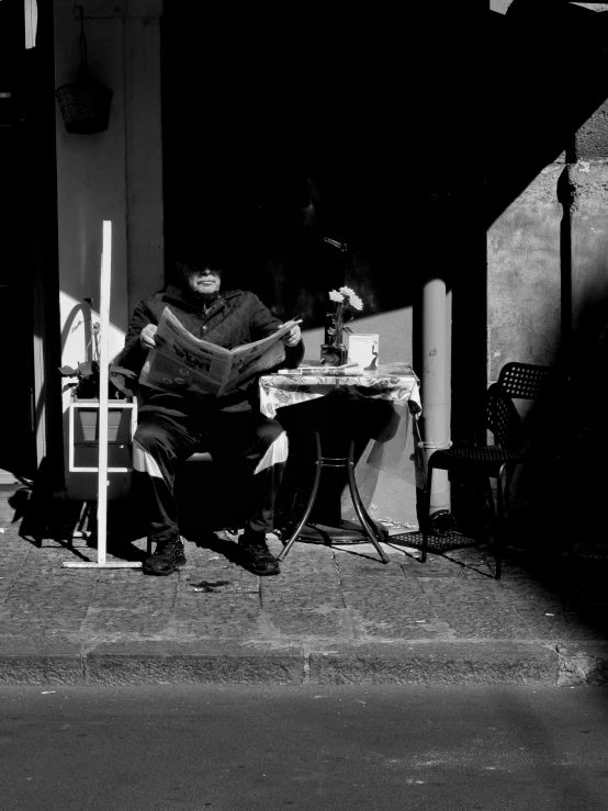 an old man sitting at a table using a phone