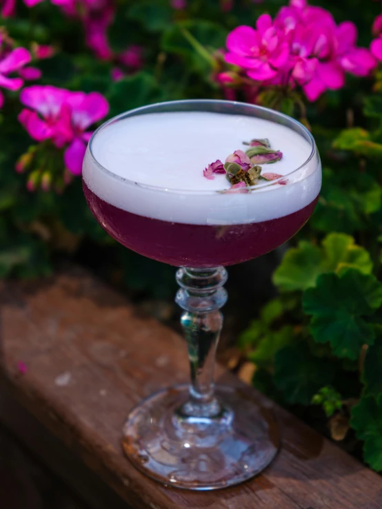 a drink in a glass with liquid and a flower on the side