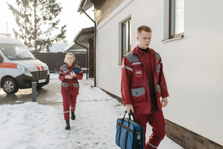 two men carrying luggage down a snowy street