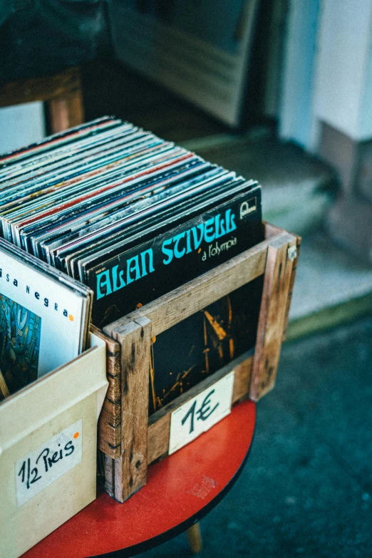 some vinyl records are stacked up in a wooden drawer