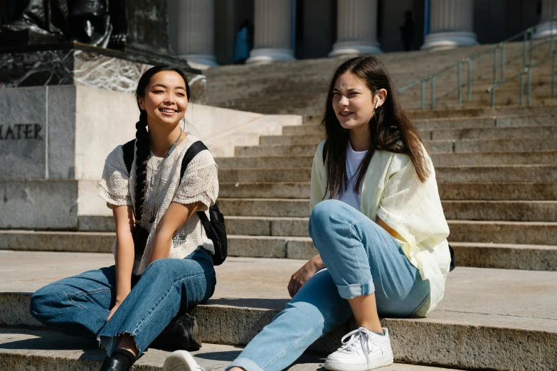 two young women sitting on the steps of a building