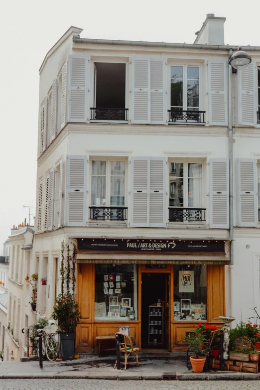 a building with shutters on it, some tables and chairs outside