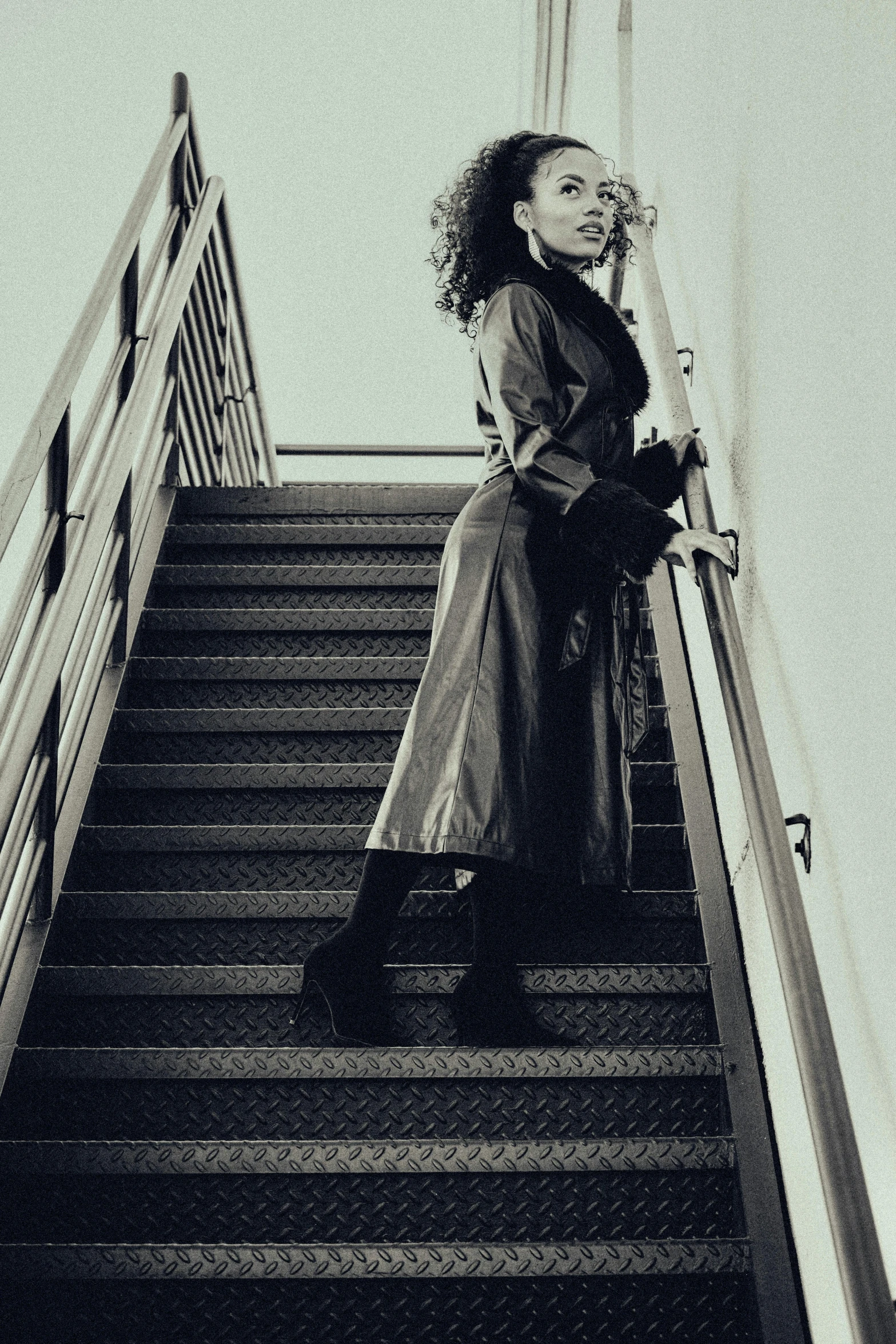 black and white pograph of woman at bottom of flight of stairs