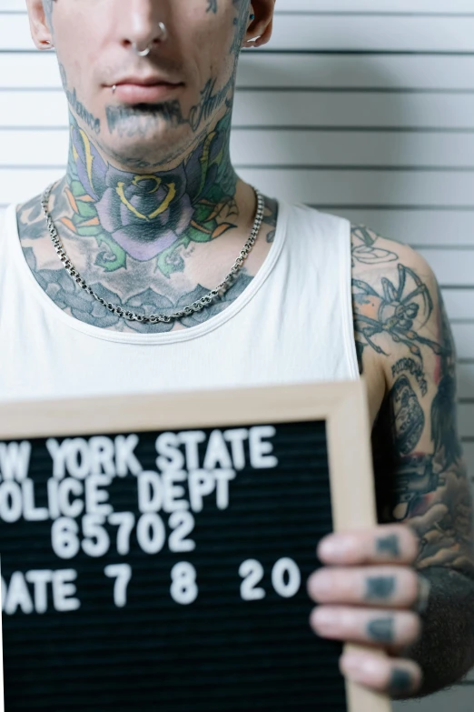 tattooed man holding a sign from a prison