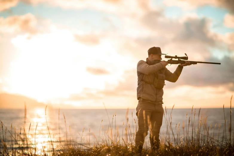 a man with an automatic rifle looking at the ocean