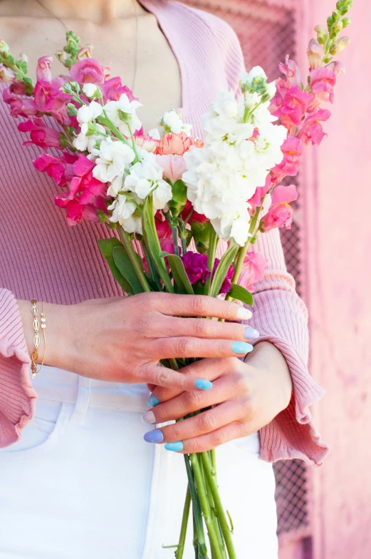 woman holding flowers from pink and white spring garden