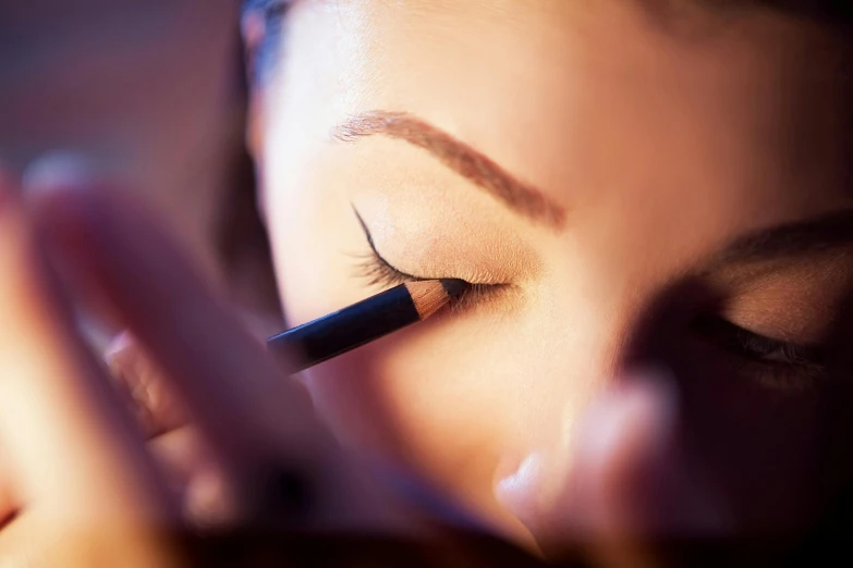 woman putting eyebrow liner on with blue pen