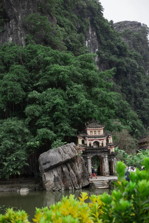 a cave on the side of a mountain next to water