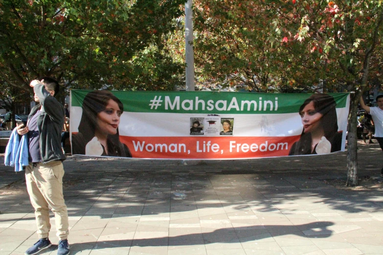 a person standing next to a banner with woman's face on it