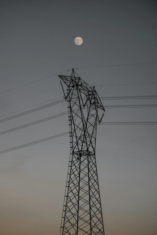 the moon is seen through the distant electricity line